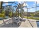 Relaxing screened-in poolside space featuring lounge chairs, lush landscaping, and picturesque water views at 2500 Jamaica St, Sarasota, FL 34231