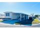 Tan single-wide manufactured home with covered carport and patio furniture at 3214 Pink Oak Ter, Sarasota, FL 34237