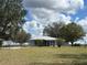 Picturesque home exterior with mature trees, a screened porch, and a sprawling lawn, blending comfort and nature at 4939 Myakka Valley Trl, Sarasota, FL 34241