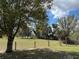 Expansive front yard featuring mature trees, a wooden fence, and a gated entry, offering privacy and country charm at 4939 Myakka Valley Trl, Sarasota, FL 34241