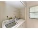 Bright laundry room features modern washer, dryer and shelving for storage at 5376 Royal Palm Ave # 5376, Sarasota, FL 34234