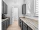 Butler's pantry with gray shaker cabinets, granite countertops, and wood floors at 10120 Carnoustie Pl, Bradenton, FL 34211