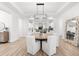 Bright dining area features a modern chandelier, wood floors, and flows into the open-concept kitchen, great for entertaining at 10120 Carnoustie Pl, Bradenton, FL 34211