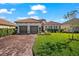 Beautiful home with a tile roof, paver driveway, manicured lawn and verdant landscaping on a sunny day at 10120 Carnoustie Pl, Bradenton, FL 34211