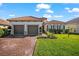 Beautiful home with a tile roof, paver driveway, manicured lawn and verdant landscaping on a sunny day at 10120 Carnoustie Pl, Bradenton, FL 34211