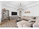 Open-concept living room features wood-look tile flooring, a large sectional sofa, and modern lighting at 10120 Carnoustie Pl, Bradenton, FL 34211