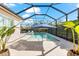 Beautiful screened-in pool with blue umbrella, surrounding greenery, and tiled deck space for outdoor enjoyment at 10120 Carnoustie Pl, Bradenton, FL 34211