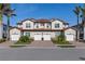 A well-maintained townhouse complex with garages, red brick driveways, and tropical landscaping against a bright blue sky at 109 Porta Vecchio Bnd # 202, Nokomis, FL 34275