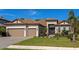 Exterior view of a two-story home with a three-car garage, tile roof, and well-manicured lawn at 16219 Tradewind Ter, Bradenton, FL 34211