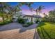 Paver driveway leading to a white home with a red tile roof, surrounded by lush tropical landscaping at 1864 Clematis St, Sarasota, FL 34239