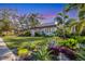 Beautifully landscaped front yard featuring tropical plants and a well-maintained lawn with a white house and red tile roof at 1864 Clematis St, Sarasota, FL 34239