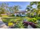 Beautifully landscaped front yard featuring tropical plants and a well-maintained lawn with a white house and red tile roof at 1864 Clematis St, Sarasota, FL 34239