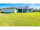 View of backyard with expansive lawn, screened lanai and exterior of home at 31 Bunker Pl, Rotonda West, FL 33947