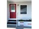 Red front door with small steps and planter at 3230 Banyan Ter, Sarasota, FL 34237