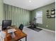 Home office or gym with wood desk, Peloton bike and green accent wall at 5307 Grove Mill Loop, Lakewood Ranch, FL 34211