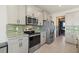 Modern kitchen featuring stainless steel appliances and green tile backsplash at 5307 Grove Mill Loop, Lakewood Ranch, FL 34211