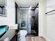 Sleek bathroom with a black-tiled shower, contemporary glass doors, and dark vanity at 712 N Elm St, Englewood, FL 34223