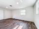 A sunlit bedroom boasts wood-look flooring, white walls, closet and a bright window at 712 N Elm St, Englewood, FL 34223