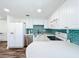 Beautiful kitchen with white cabinets, countertops, modern appliances, and turquoise tile backsplash at 712 N Elm St, Englewood, FL 34223