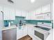 Bright kitchen featuring white cabinets, updated appliances, and stylish turquoise backsplash at 712 N Elm St, Englewood, FL 34223