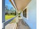 View from the porch of home with white wood and blue wall paint, overlooking a well manicured green yard at 712 N Elm St, Englewood, FL 34223