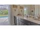 Bathroom vanity with stone countertops, decorative wall hangings, and a view of the pool area at 16307 29Th E Ct, Parrish, FL 34219