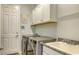 Laundry room features a utility sink, modern washer and dryer, and white cabinets for storage at 16307 29Th E Ct, Parrish, FL 34219