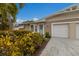 Tan house with white garage doors, landscaping, and palm trees at 205 82Nd St # East, Holmes Beach, FL 34217