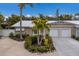 Tan house with white garage doors, landscaping, and palm trees at 205 82Nd St # East, Holmes Beach, FL 34217