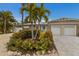 Tan house with white garage doors, landscaping, and palm trees at 205 82Nd St # East, Holmes Beach, FL 34217
