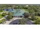 Aerial view of the clubhouse with a green roof, surrounded by lush landscaping, lake and palm trees at 6211 Skyward Ct, Bradenton, FL 34203
