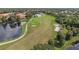 Aerial view of a lush green golf course adjacent to a serene lake and surrounded by trees and homes at 6211 Skyward Ct, Bradenton, FL 34203