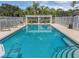 Community pool with clear blue water, fenced perimeter, lounge chairs, and palm trees, creating a relaxing environment at 6211 Skyward Ct, Bradenton, FL 34203