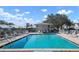 Community pool with chairs, tables and a pool house with clear blue sky at 6609 Stone River Rd # 206, Bradenton, FL 34203