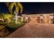 Elegant home exterior at night, showcasing landscaping and a brick driveway at 7033 Brier Creek Ct, Lakewood Ranch, FL 34202