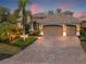Beautiful home exterior, three-car garage and a large brick driveway at dusk at 7033 Brier Creek Ct, Lakewood Ranch, FL 34202