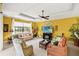 Bright living room with comfy seating, large TV, and yellow walls at 7033 Brier Creek Ct, Lakewood Ranch, FL 34202