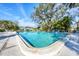 Community pool with crystal clear water, surrounded by mature trees and lounge chairs in a serene setting at 7422 W Country Club N Dr, Sarasota, FL 34243