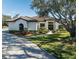 White one-story home with brown roof, landscaping, and driveway at 1060 Water Oak Ne Ct, St Petersburg, FL 33703