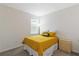 Cozy bedroom with a bright yellow bedspread, a window with blinds, and a simple wooden nightstand at 11794 Little River Way, Parrish, FL 34219