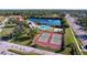 Wide aerial shot of a community featuring tennis courts, a pool, a lake, and well-kept grounds at 1210 56Th W St # 1210, Bradenton, FL 34209