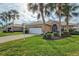 House exterior showcasing a tan facade, white garage door, and palm trees at 1364 Berkshire Ct, Venice, FL 34292