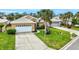 Tan house with white garage door, palm trees, and well-manicured lawn at 1364 Berkshire Ct, Venice, FL 34292