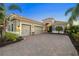 A stunning home with a three-car garage, paver driveway, lush landscaping, and warm lighting at 15326 Castle Park Ter, Lakewood Ranch, FL 34202