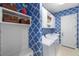 Bright laundry room with blue patterned walls, shelving, a utility sink, and modern white washer and dryer at 15326 Castle Park Ter, Lakewood Ranch, FL 34202