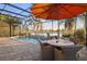 Inviting screened-in pool area with waterfall feature, a shaded table setting, and a view of the lush landscaping at 15326 Castle Park Ter, Lakewood Ranch, FL 34202