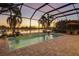 An outdoor enclosed pool with a waterfall feature, surrounded by patio pavers and palm trees at sunset at 15326 Castle Park Ter, Lakewood Ranch, FL 34202