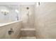 Tiled shower with a built-in bench, handheld shower fixture, and glass partition in a neutral, modern bathroom at 15326 Castle Park Ter, Lakewood Ranch, FL 34202