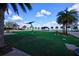 Park view of the manicured lawn, with benches, playground, and palm trees against a blue sky at 17395 Palmetto Pass Ln, Punta Gorda, FL 33982