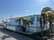 White single-wide home with teal accents, covered porch, and palm trees at 2601 Gulf N Dr # 427, Bradenton Beach, FL 34217